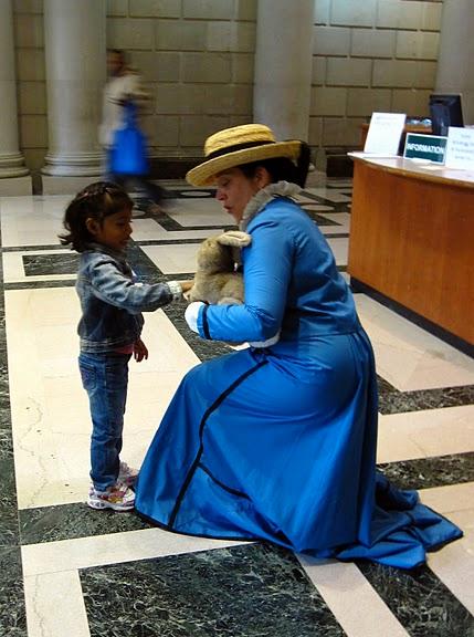 A member of the Beatrix Potter Society dressed as Beatrix, with Peter Rabbit, greets a young library patron. Photo courtesy of Jenny Walker.